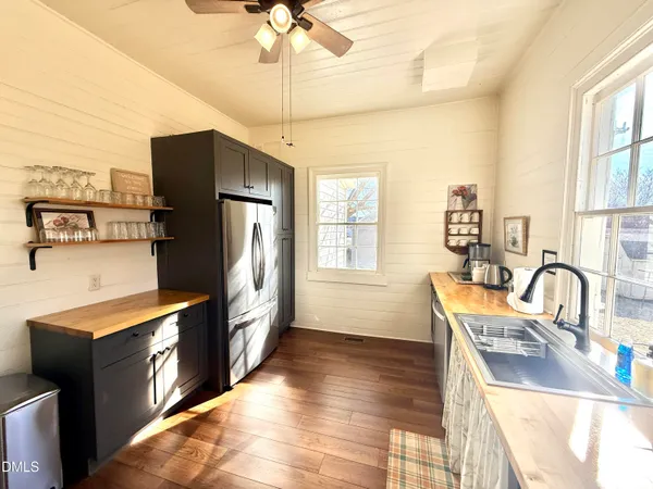 a kitchen with stainless steel appliances granite countertop a refrigerator a sink a stove and island with wooden floor