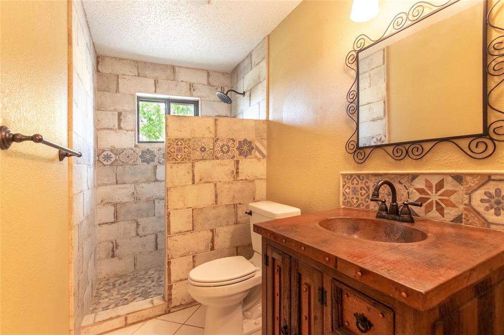 308 Sanders Road Denton, TX 76210 - Photo 10 of 31 Custom vanity with an integrated copper sink, decorative tile backsplash, and a framed wall mirror