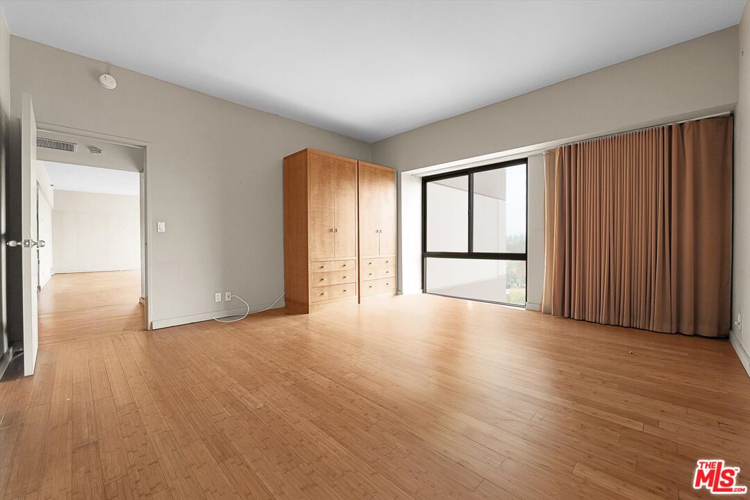 10445 Wilshire Boulevard, Unit 904 Los Angeles, CA 90024 - Photo 20 of 40 an empty room with wooden floor and windows with curtains