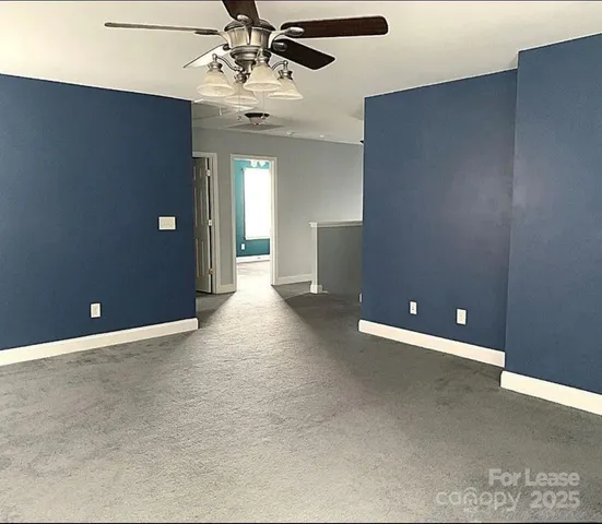 a view of an empty room with a chandelier fan