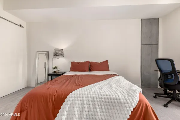 a bedroom with a bed a chair and painting on the wall