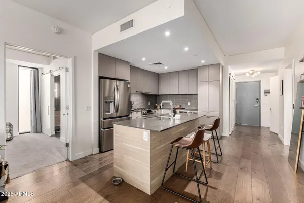 a kitchen with stainless steel appliances kitchen island granite countertop a refrigerator and a stove top oven