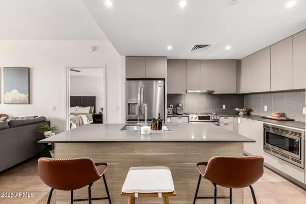 a kitchen with stainless steel appliances granite countertop a stove a sink a refrigerator a dining table and chairs