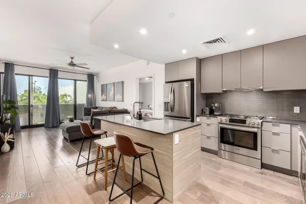 a kitchen with stainless steel appliances granite countertop a stove top oven a sink dishwasher a dining table and chairs with wooden floor