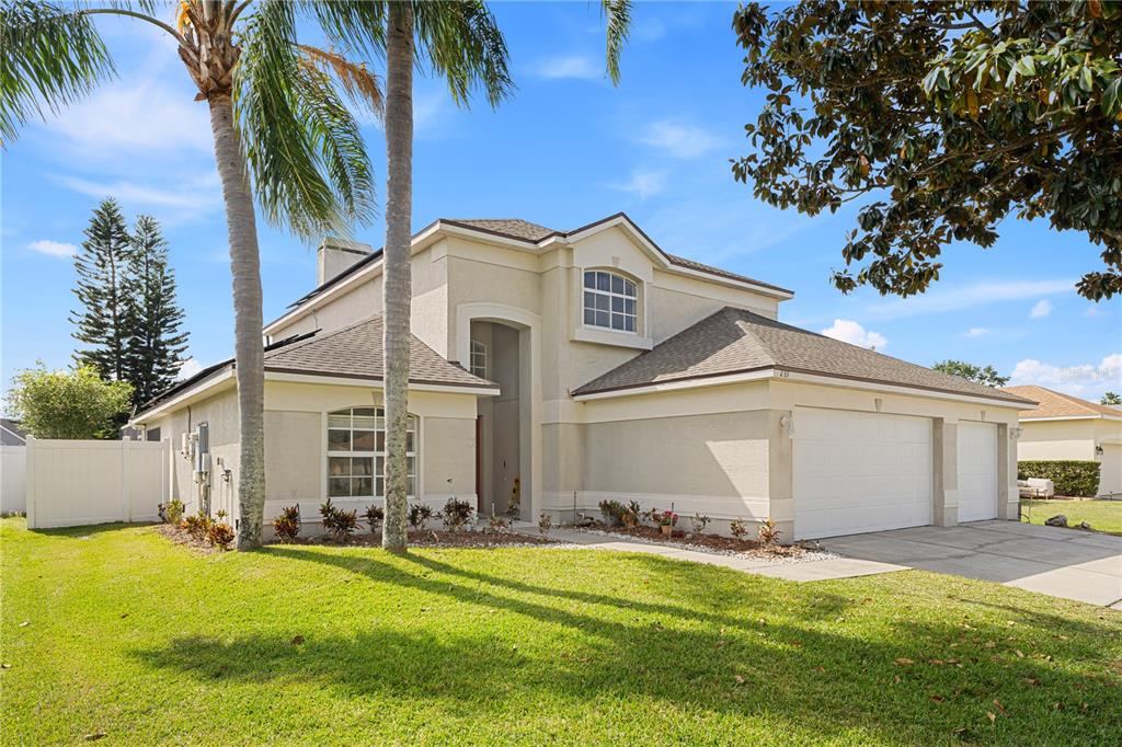a view of a white house with a big yard and palm trees