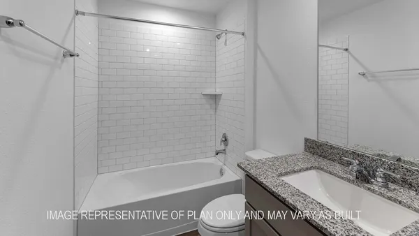 a bathroom with a granite countertop bathtub shower sink vanity and toilet