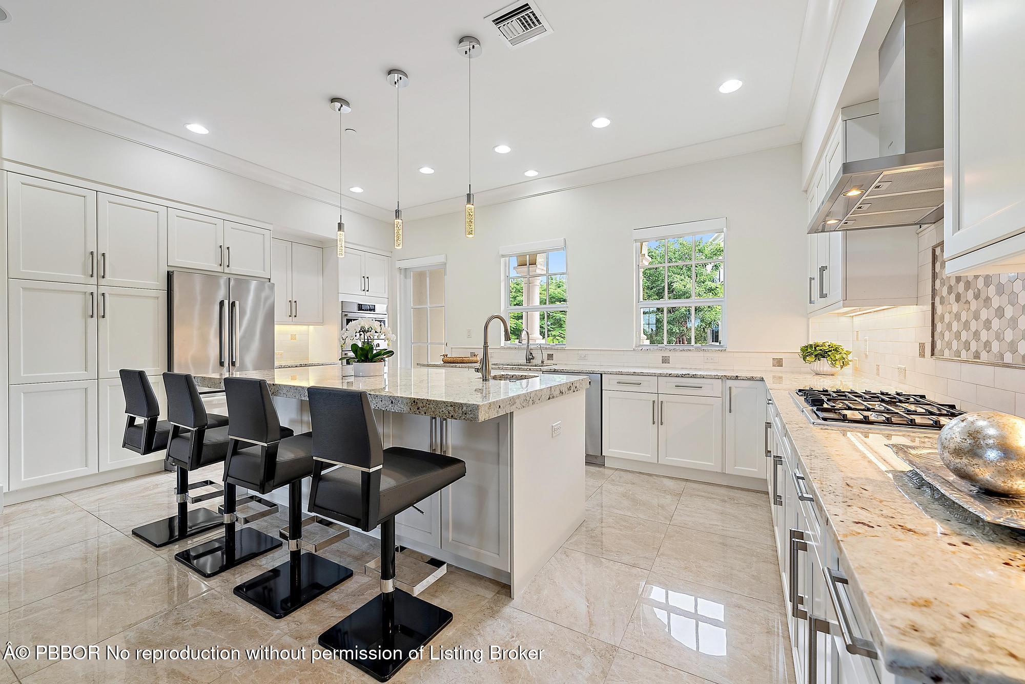 138 Tierra Lane, Unit 6 Jupiter, FL 33477 - Photo 9 of 41 a kitchen with stainless steel appliances kitchen island granite countertop a stove a sink a refrigerator and a dining table with wooden floor