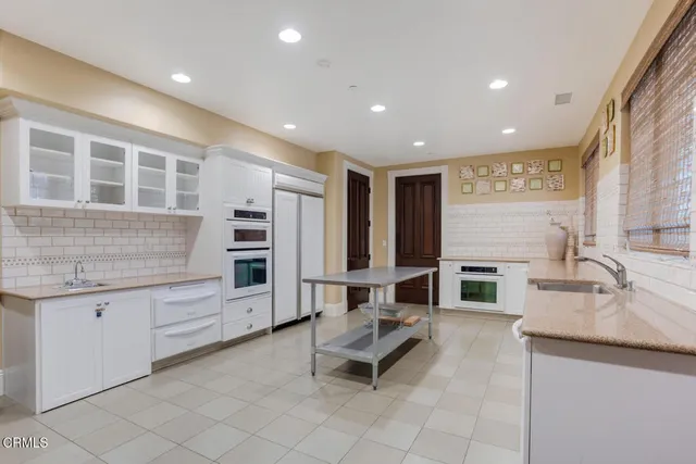 a living room with stainless steel appliances kitchen island granite countertop a sink and cabinets