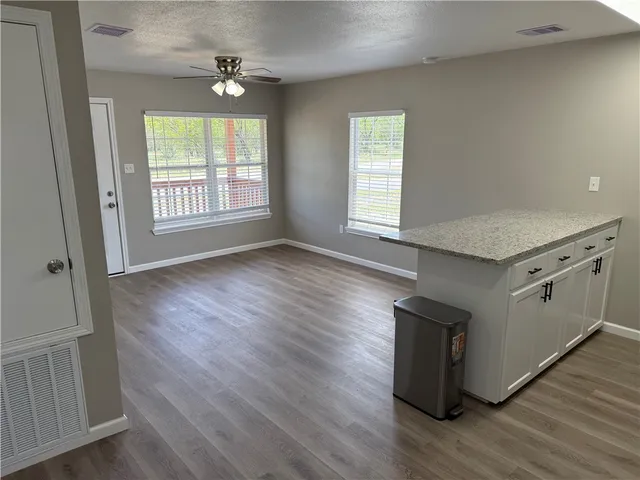 an empty room with wooden floor cabinet and windows
