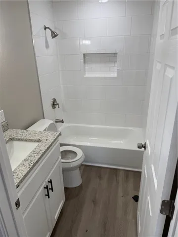 a bathroom with a granite countertop sink a toilet and bathtub