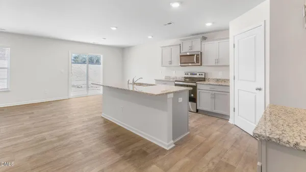 a kitchen with stainless steel appliances granite countertop a stove top oven a sink and white cabinets
