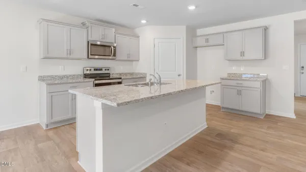 a kitchen with kitchen island a sink a stove a microwave and wooden cabinets
