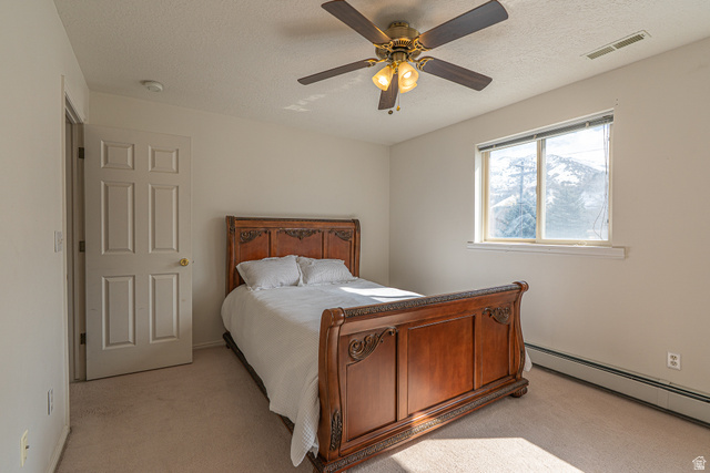 1045 Fox Farm Road Logan, UT 84321 - Photo 41 of 65 Bedroom featuring a baseboard heating unit, a textured ceiling, light carpet, and ceiling fan
