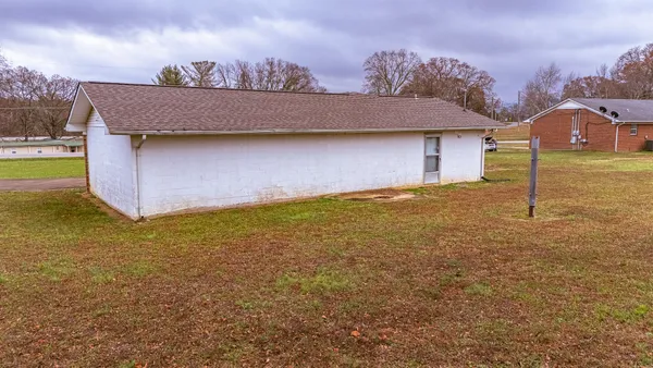 a view of a house with a yard and a large tree