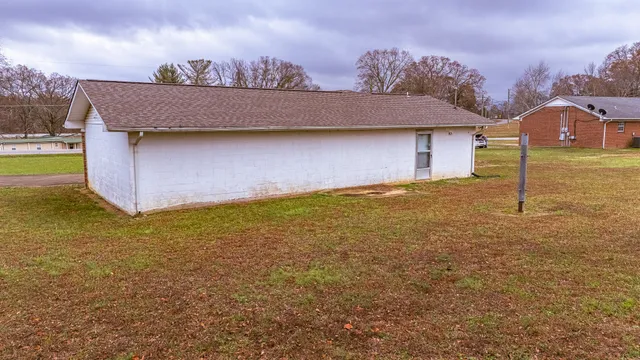 a view of a house with a yard and a large tree