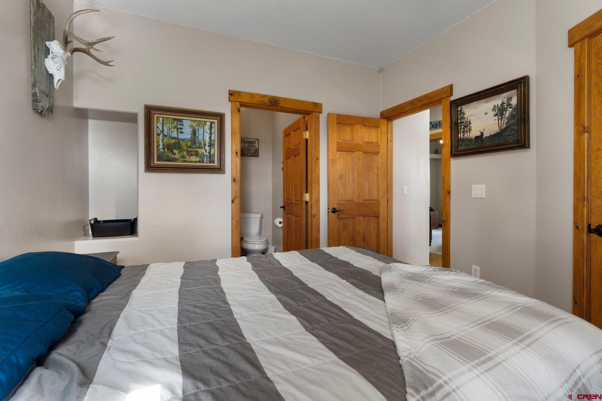 16132 Ee Road Pleasant View, CO 81331 - Photo 22 of 35 a bedroom with a large bed and a chandelier