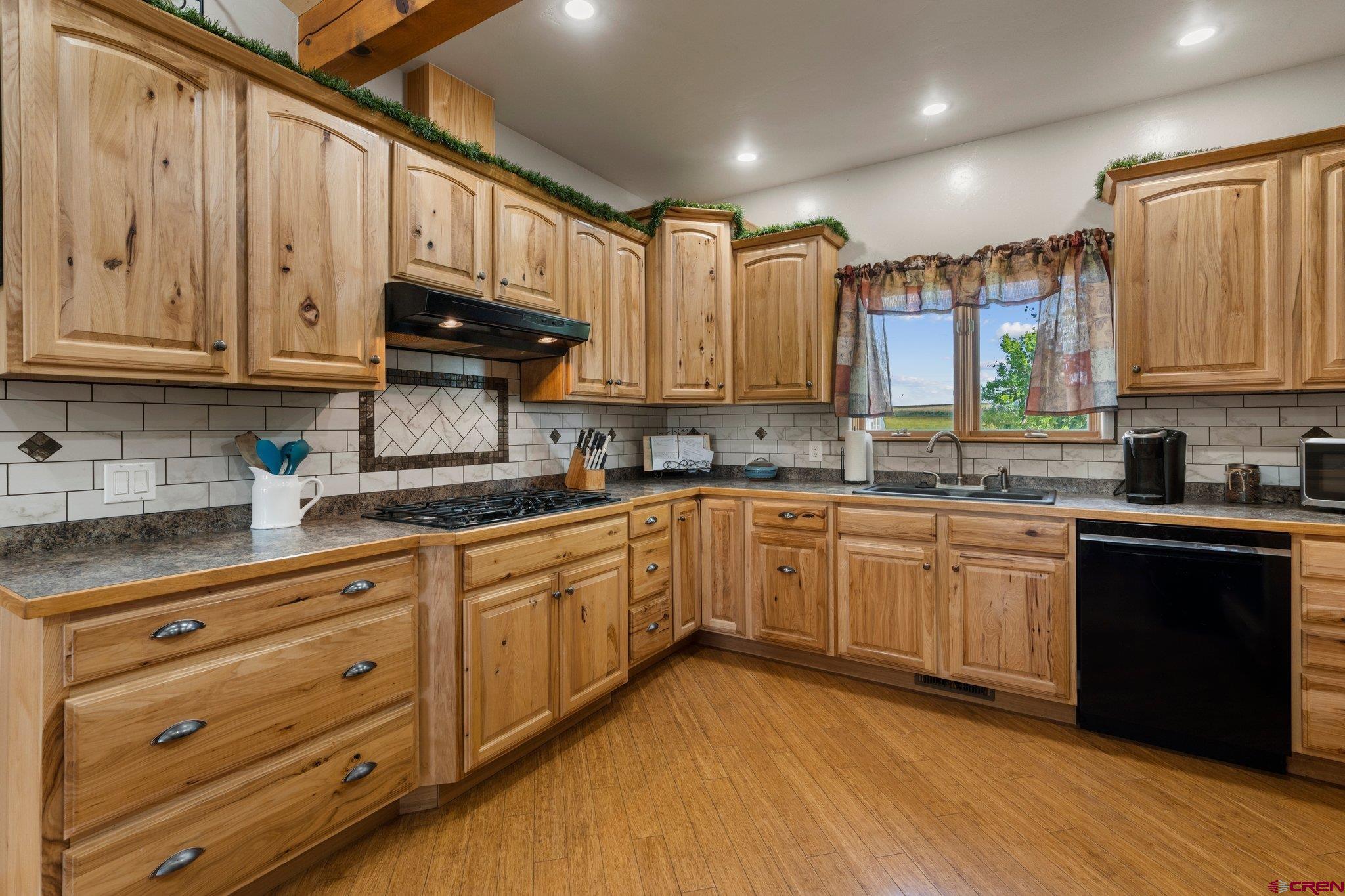 16132 Ee Road Pleasant View, CO 81331 - Photo 10 of 35 a kitchen with stainless steel appliances granite countertop wooden cabinets a sink and dishwasher with wooden floor