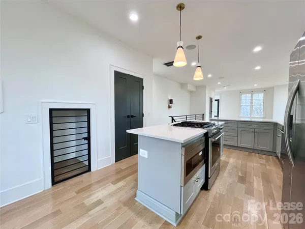 a kitchen with stainless steel appliances granite countertop a sink a stove and a wooden floors