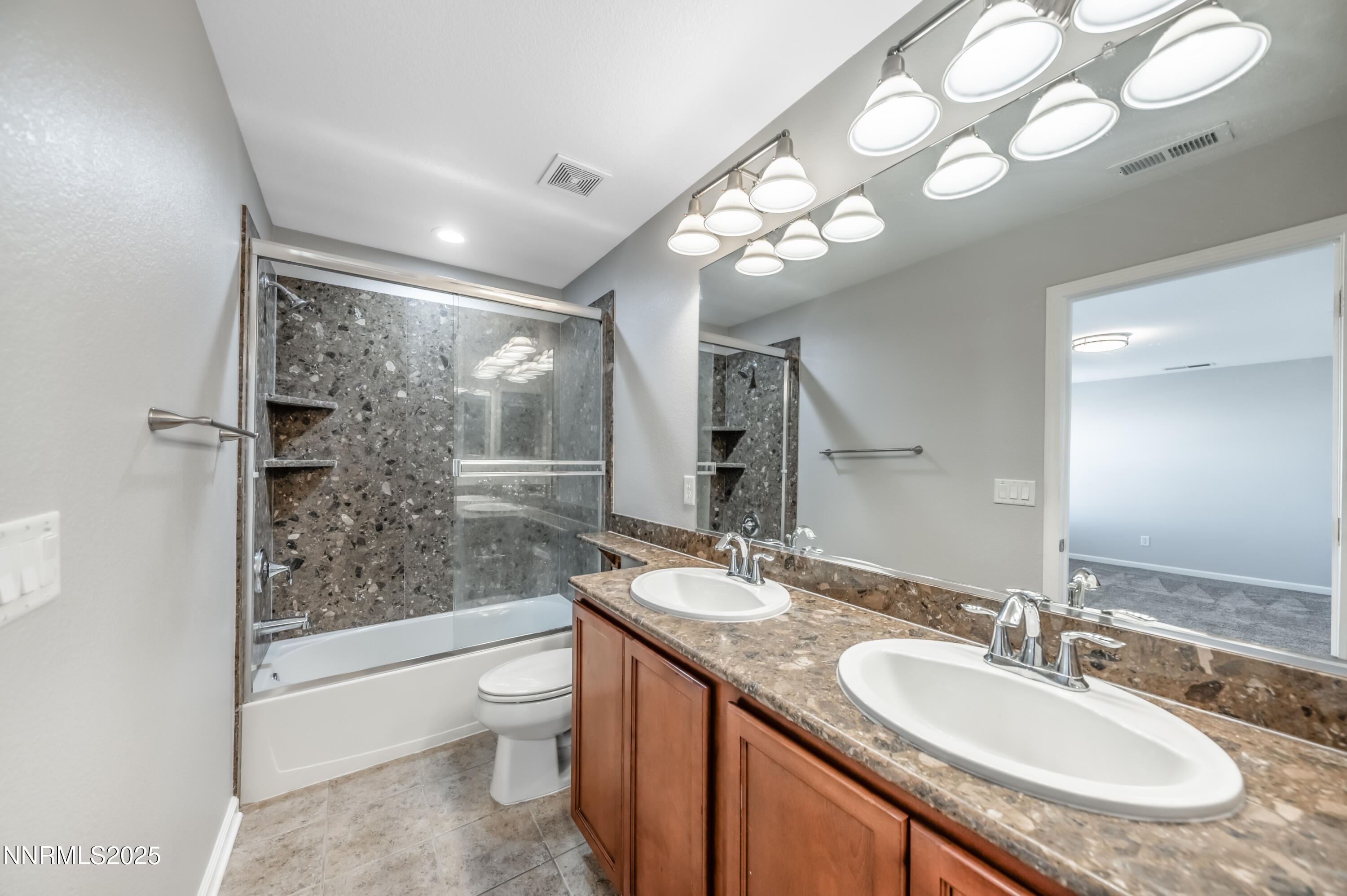 8905 Convair Way Reno, NV 89506 - Photo 25 of 38 a bathroom with a granite countertop sink a toilet a mirror a vanity and shower