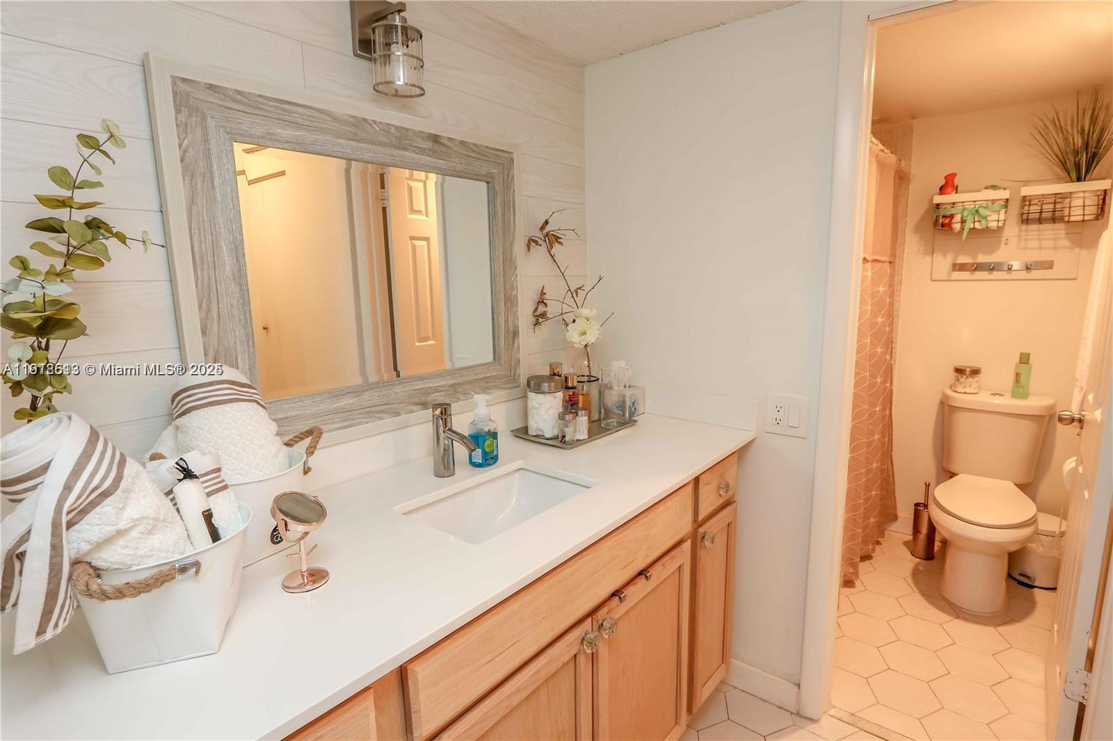 9150 Lime Bay Boulevard, Unit 212 Tamarac, FL 33321 - Photo 18 of 21 a bathroom with a sink a toilet and a mirror