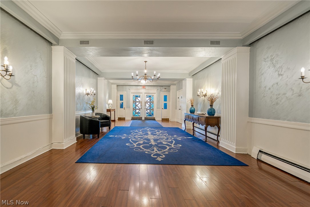 13800 Fairhill Road, Unit 306 Cleveland, OH 44120 - Photo 4 of 48 Foyer entrance featuring suspended lighting, dark wood-style flooring, ornamental molding, a baseboard radiator, and wainscoting