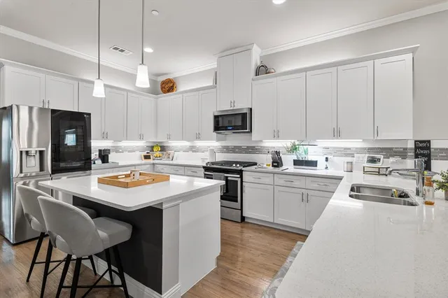 a kitchen with a sink a stove a refrigerator and white cabinets with wooden floor