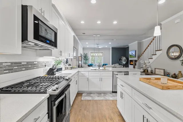 a kitchen with stainless steel appliances granite countertop a stove a sink a microwave a refrigerator a stove and white cabinets