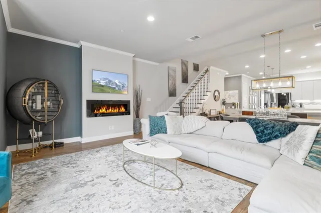 a living room with furniture kitchen view and a wooden floor