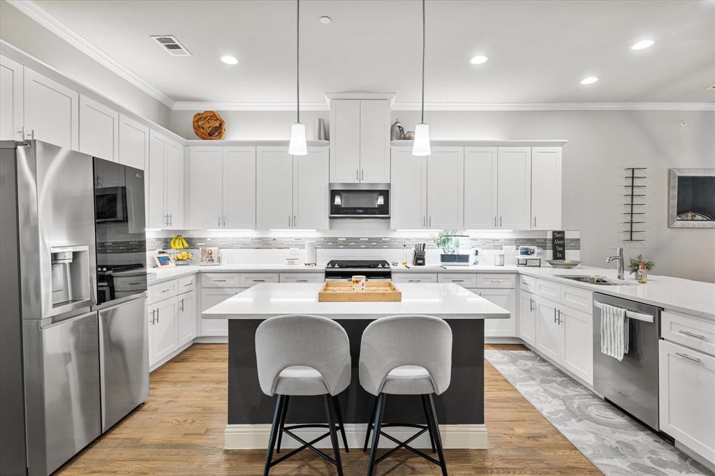 6013 Page Street Frisco, TX 75034 - Photo 2 of 39 a kitchen with stainless steel appliances granite countertop a stove top oven a refrigerator a sink and white cabinets with wooden floor