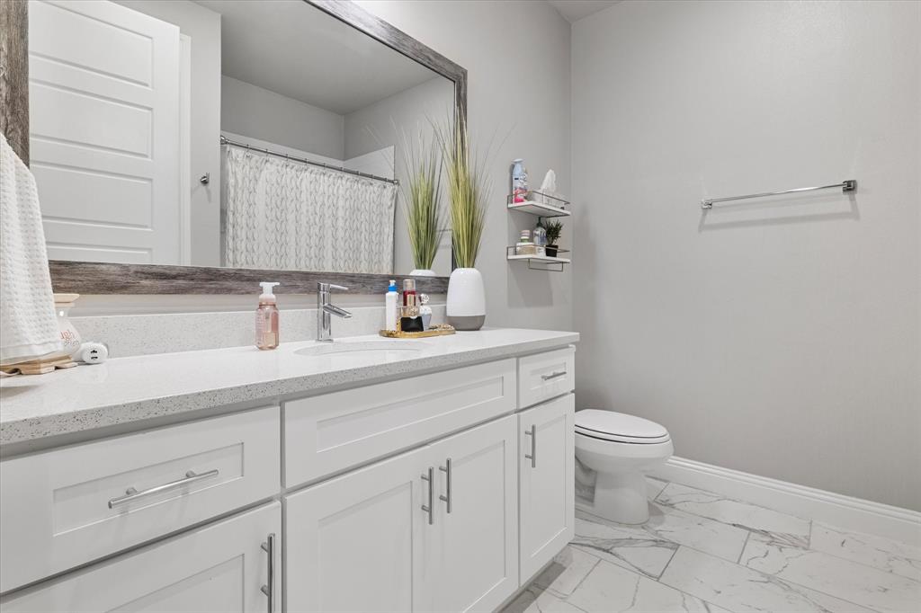 6013 Page Street Frisco, TX 75034 - Photo 9 of 39 a bathroom with a sink a toilet and a mirror