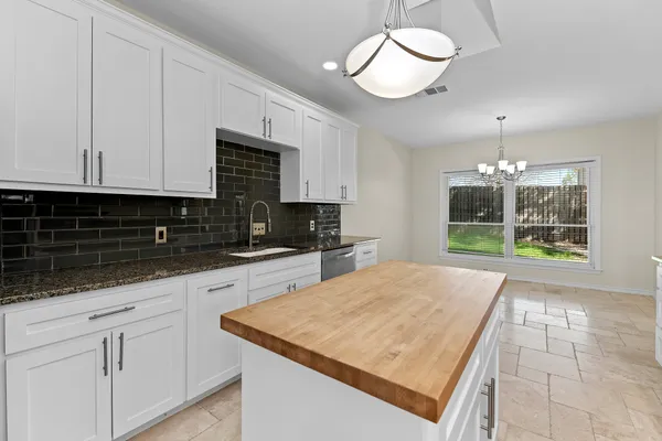 a kitchen with granite countertop a stove a sink and a white cabinets