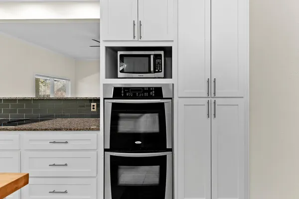a kitchen with granite countertop white cabinets and stainless steel appliances