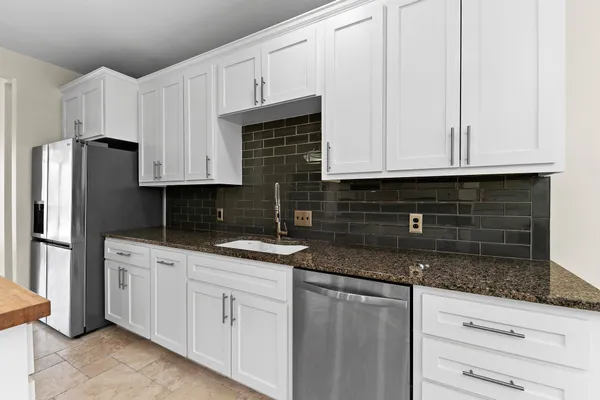 a kitchen with granite countertop white cabinets and stainless steel appliances