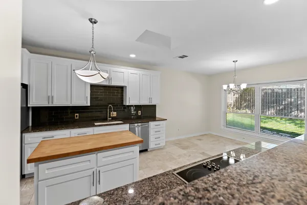 a kitchen with kitchen island granite countertop a sink a counter top space appliances and cabinets