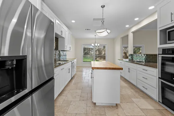 a large kitchen with a large counter top space a sink stainless steel appliances and cabinets