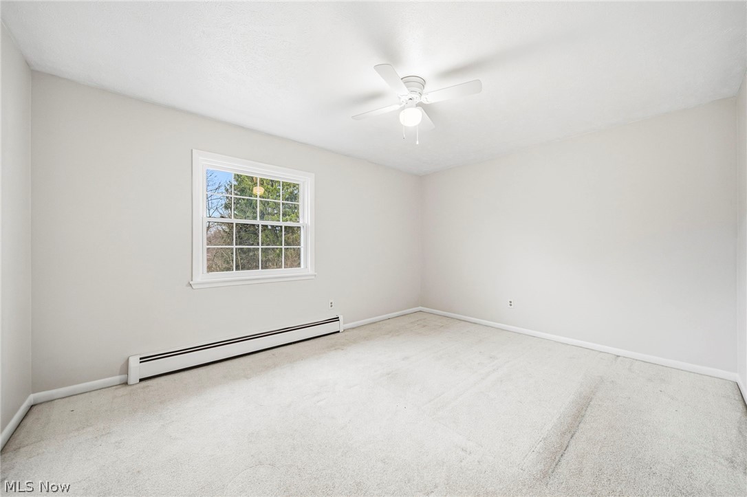 10397 Prouty Road Painesville, OH 44077 - Photo 10 of 32 Spare room with baseboard heating, light colored carpet, and a ceiling fan