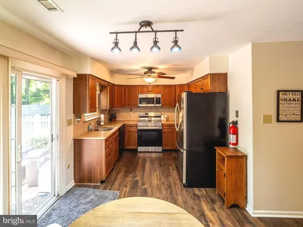 a kitchen with granite countertop a refrigerator a sink dishwasher a stove and a dining table with wooden floor