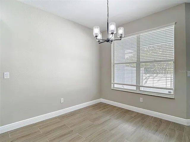 an empty room with wooden floor chandelier fan and windows