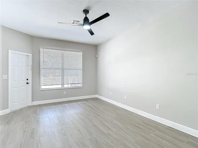 a view of an empty room with wooden floor and a window