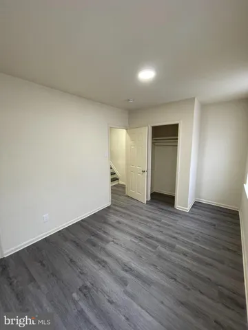 a view of an empty room with wooden floor and closet