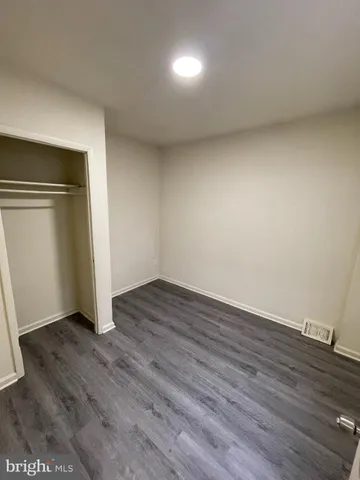 a view of an empty room with wooden floor and closet