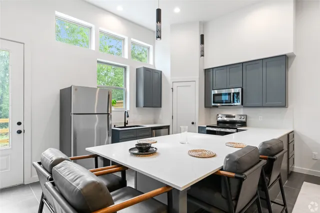 a kitchen with stainless steel appliances granite countertop a stove a refrigerator a sink a dining table and chairs with wooden floor