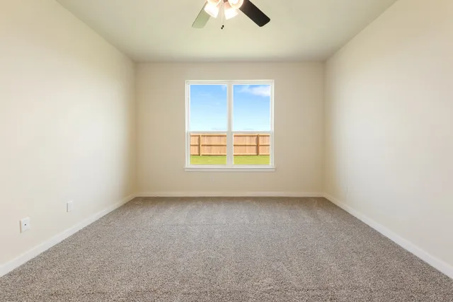 an empty room with a window and a ceiling fan