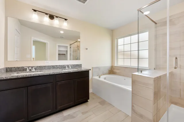 a bathroom with a granite countertop bathtub a sink and a large mirror
