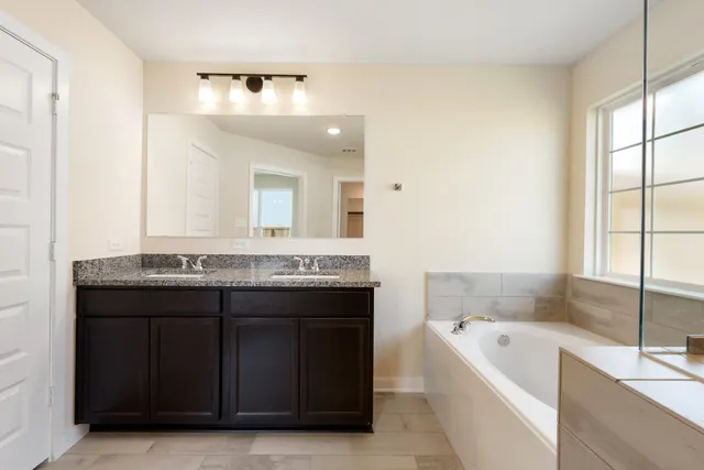 a bathroom with a granite countertop bathtub a sink and a large mirror