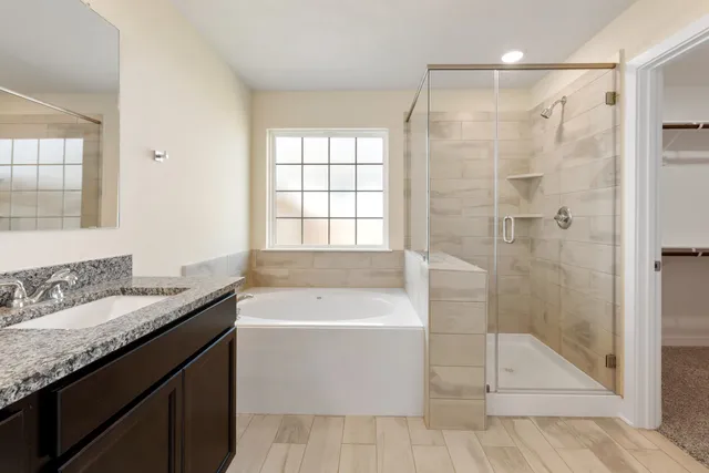 a bathroom with a granite countertop sink a mirror a bathtub and next to a window