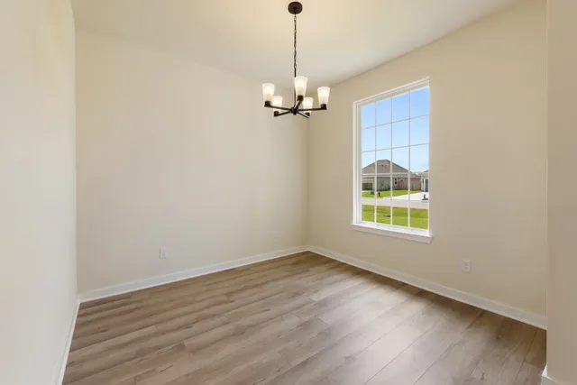 an empty room with wooden floor ceiling fan and window