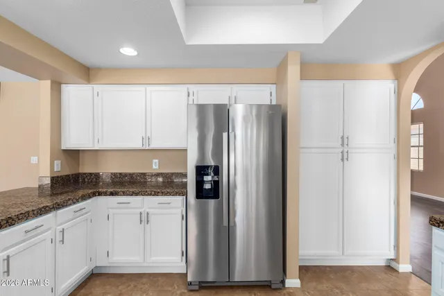 a kitchen with granite countertop a refrigerator sink and cabinets