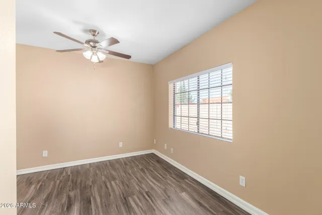 an empty room with wooden floor fan and windows