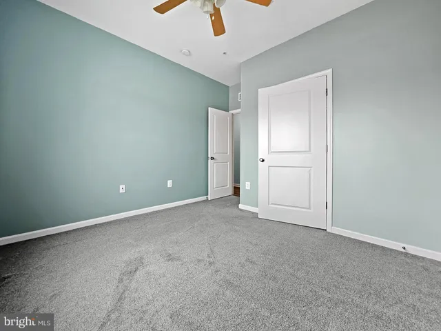 an empty room with ceiling fan and window